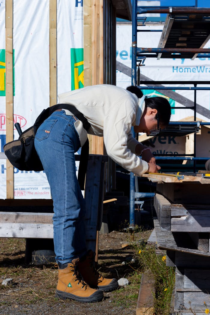 About A person engaged in woodworking at a construction site, wearing boots and jeans.