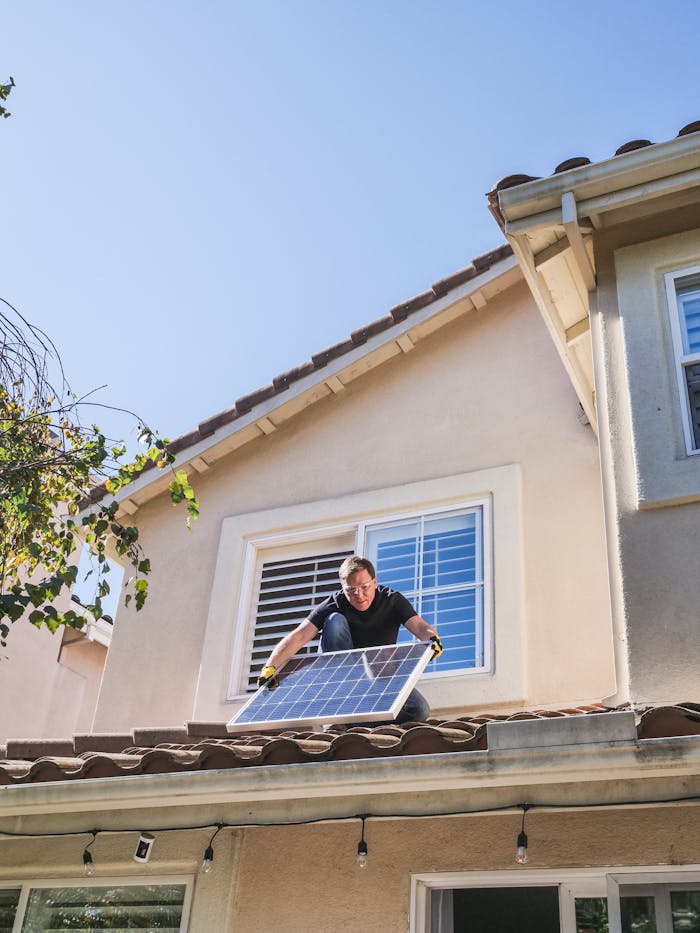 Home A worker installs a solar panel on a residential rooftop, showcasing renewable energy technology.